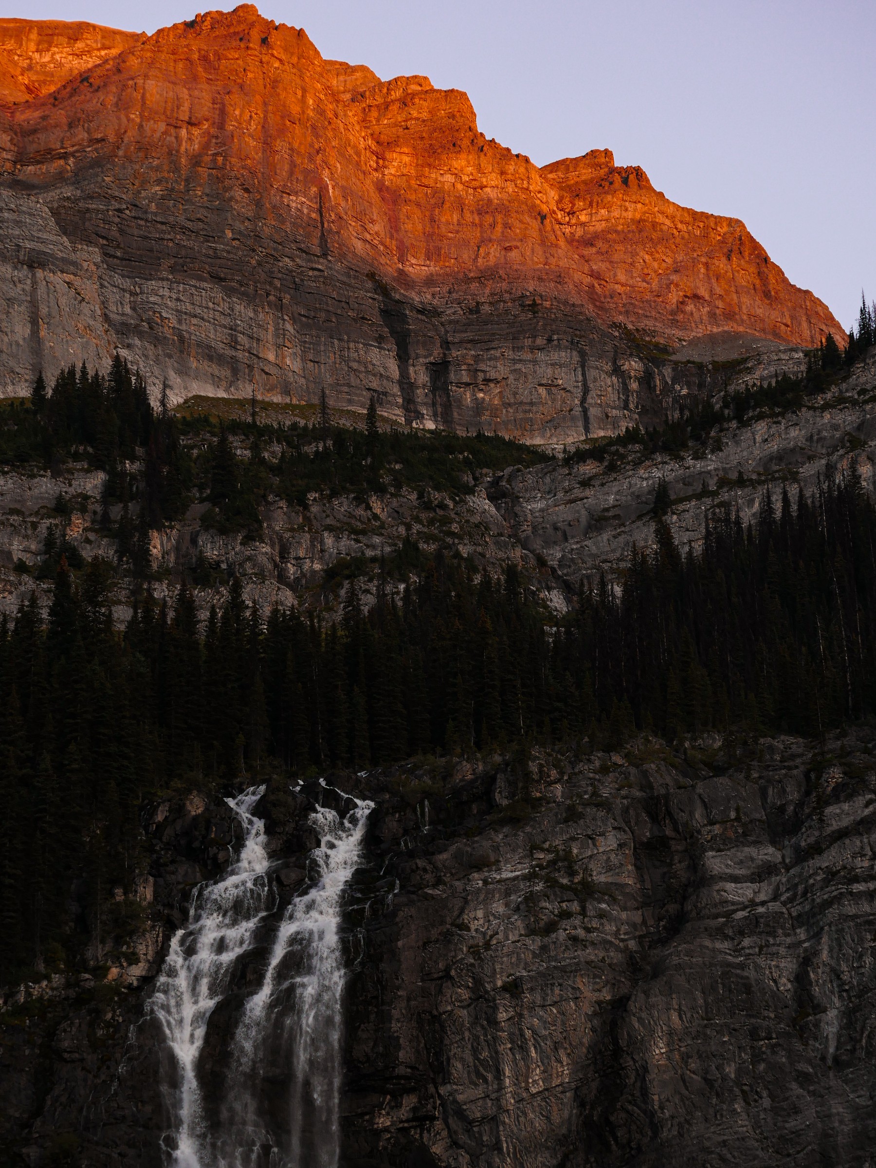 Alpenglow on a rock face above a waterfall, photo by Byron Lambert
