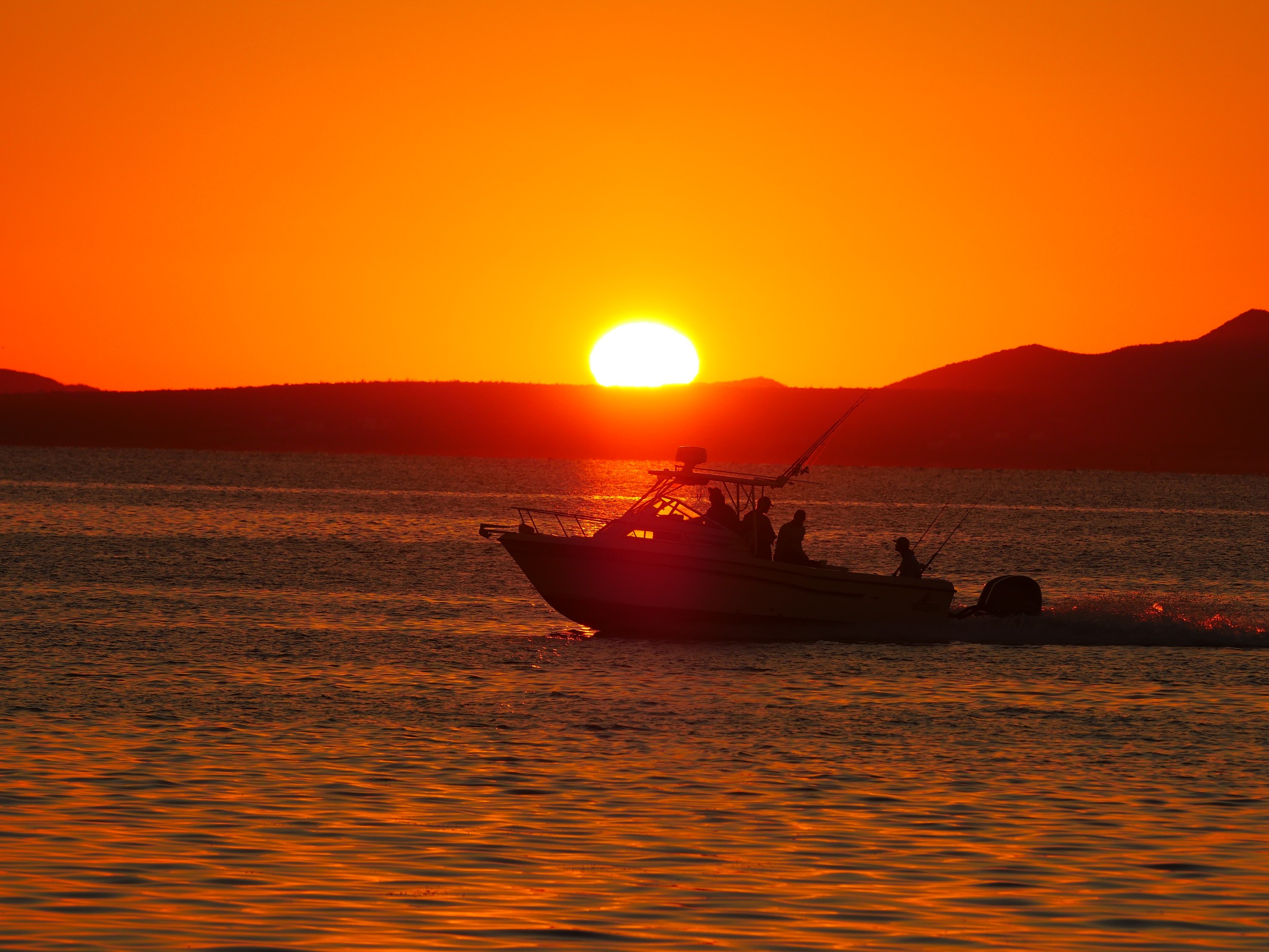 A boat crossing in front of the setting sun, photo by Byron Lambert